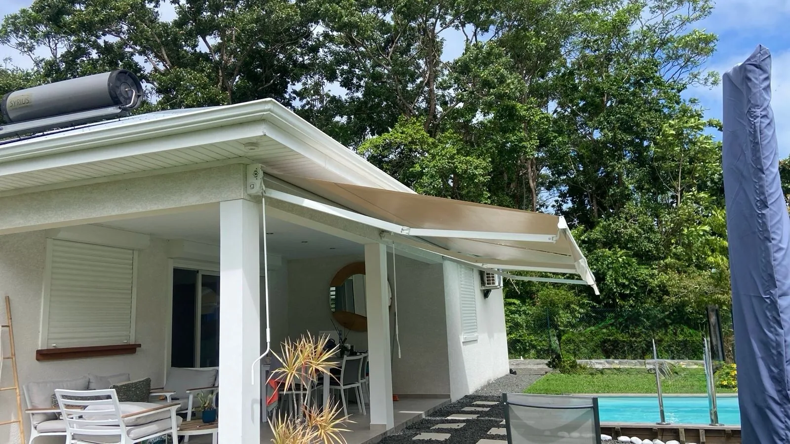 Store banne à bras invisibles déployé au-dessus de la terrasse d'une villa avec piscine